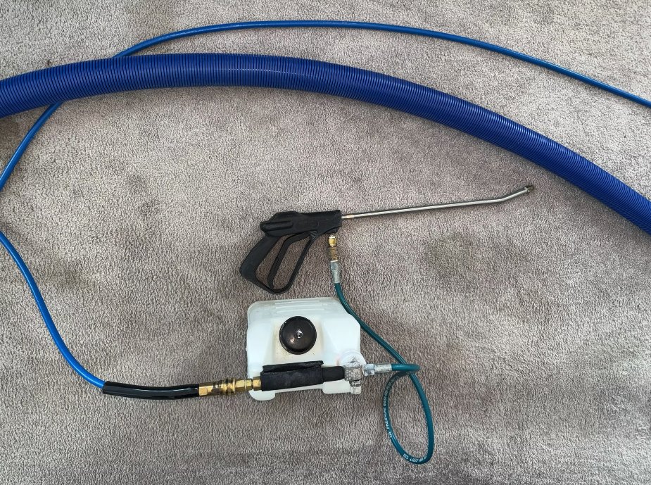 Carpet cleaning wand, hoses and sprayer on freshly cleaned carpet